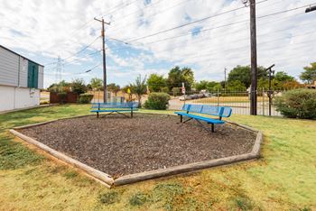 two blue benches in a fenced in area with a gravel area and a playground