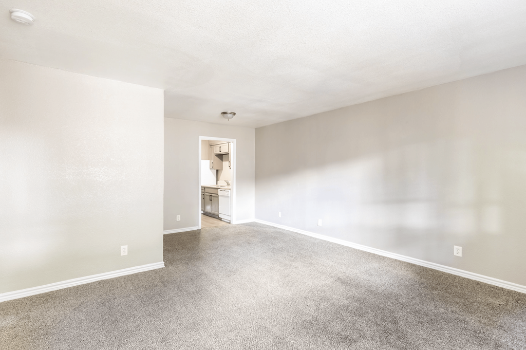 A spacious room with a carpeted floor and a doorway leading to another room.
