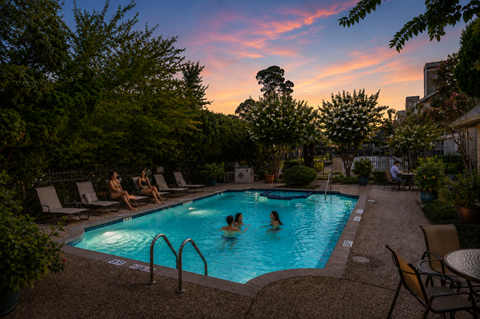 Outdoor swimming pool at sunset with lounge seating at Woodway Gardens Townhomes Apartments, Texas, 77063
