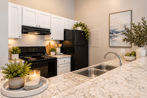 A modern kitchen with a black refrigerator and white cabinets.