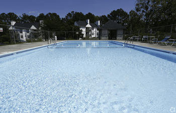 a large swimming pool with chairs and a fence around it