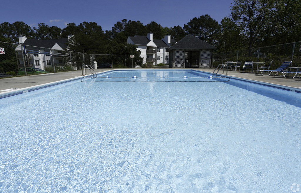 a large swimming pool with chairs and a fence around it