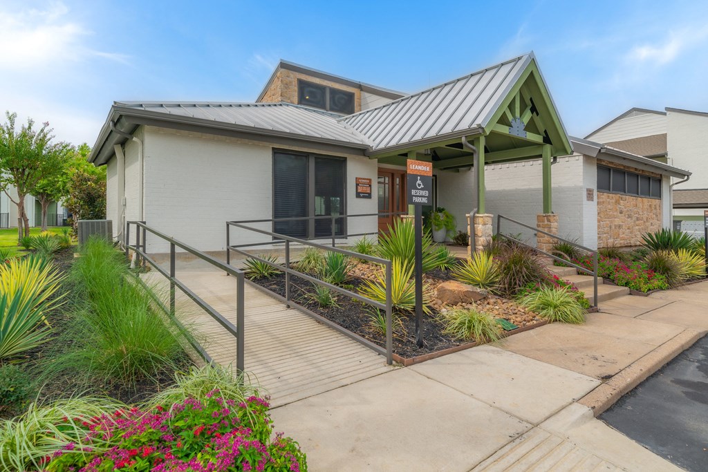the front of a building with a porch and a walkway with plants