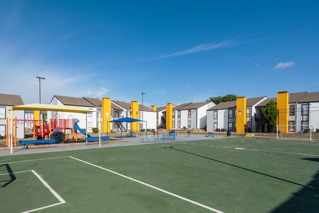 a tennis court with apartments in the background at Helios, Dallas, 75240