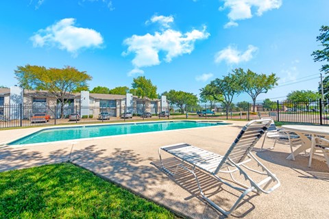 Swimming pool with lounge chairs and mature trees at Marshall Apartments, Texas