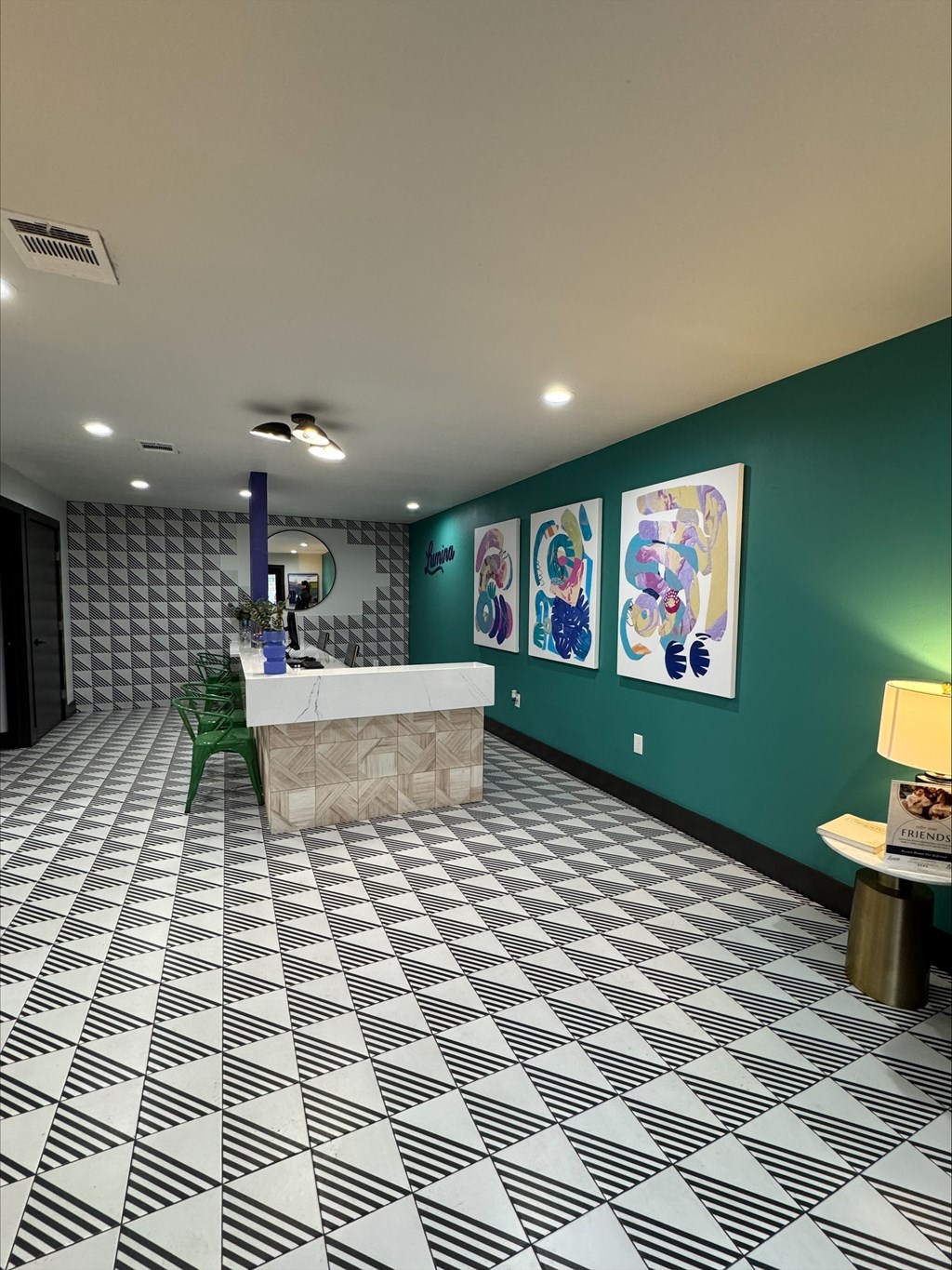 A reception area with a white reception desk and a green chair.