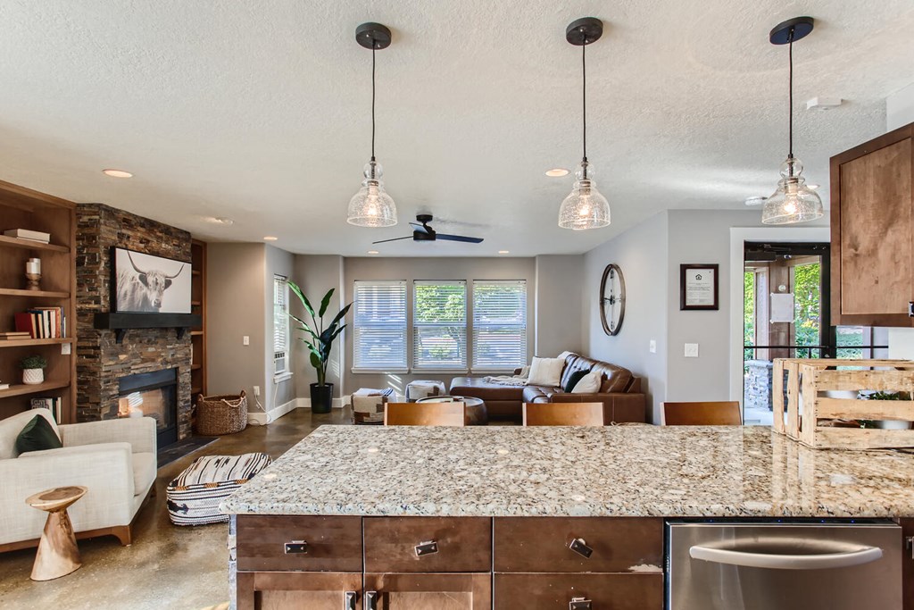 a kitchen with a granite counter top and a living room with a fireplace