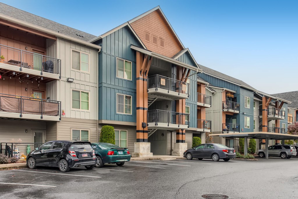a row of apartment buildings with cars parked in front