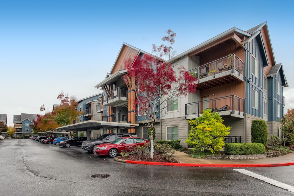 a street view of an apartment building with cars parked in front