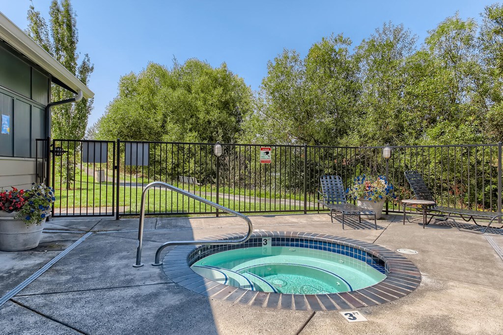 a hot tub in a patio with a fence and trees