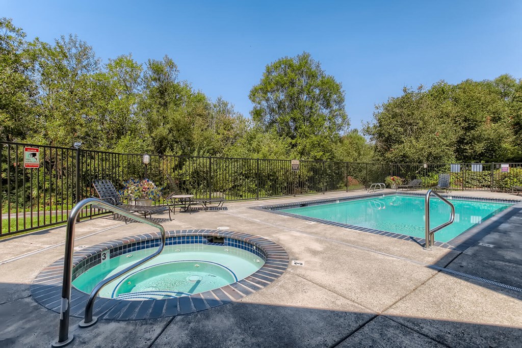 a swimming pool with a hot tub and a wrought iron fence