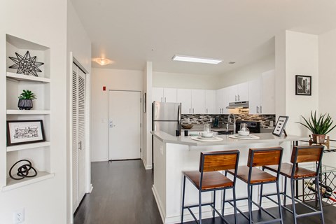 a kitchen with a bar and stools and a refrigerator