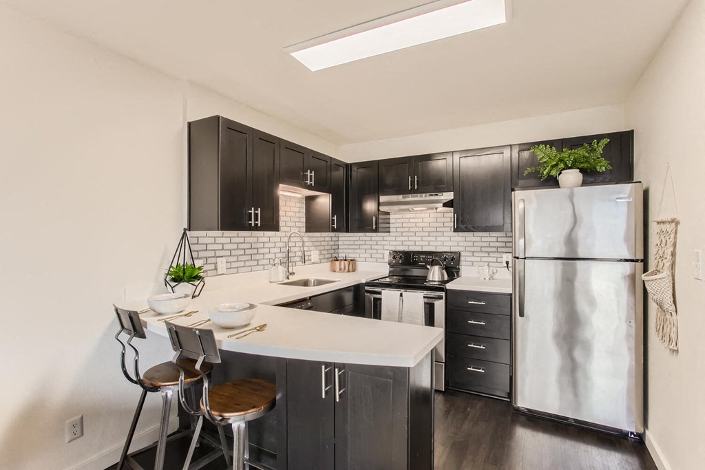 a kitchen with black cabinets and a stainless steel refrigerator