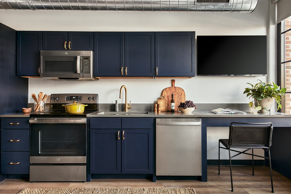 a kitchen with navy blue cabinets and stainless steel appliances