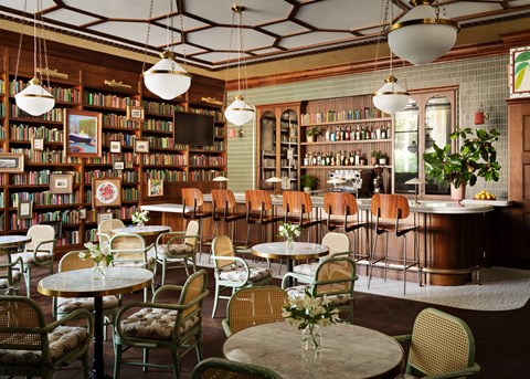 a restaurant with tables and chairs and a library filled with books