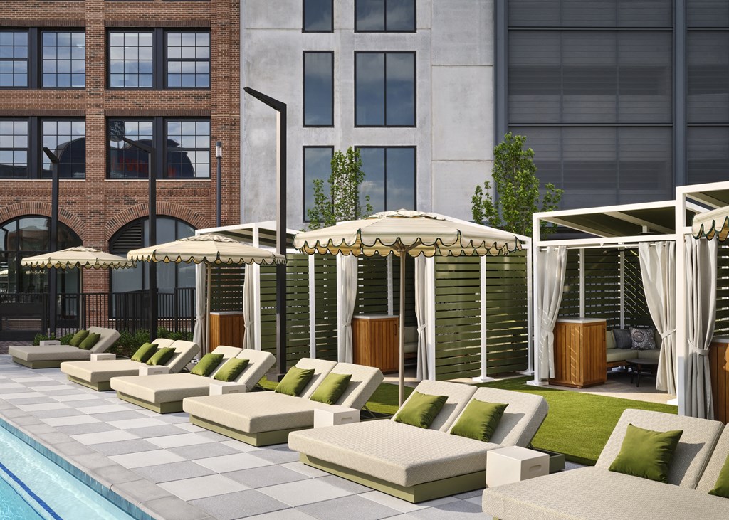 a row of lounge chairs and umbrellas next to a pool