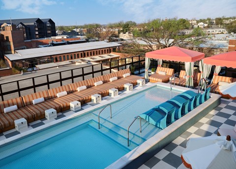 A pool with blue water and orange lounge chairs.
