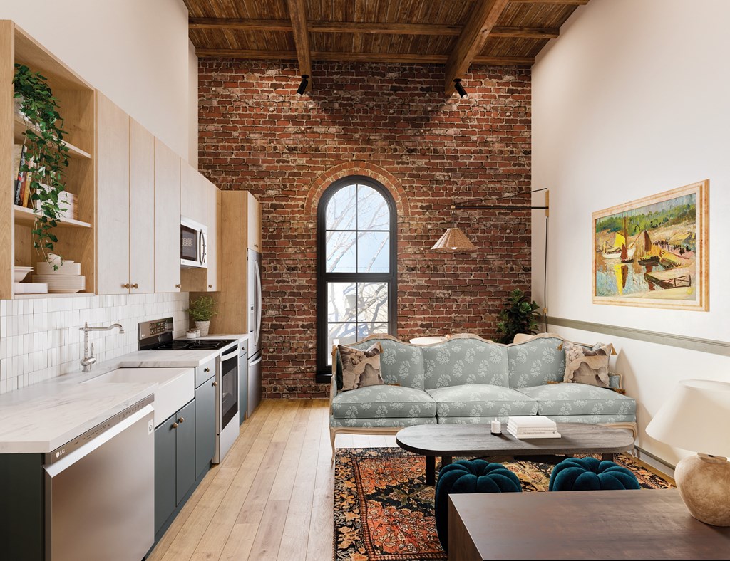 a living room with a couch and a kitchen with an exposed brick wall