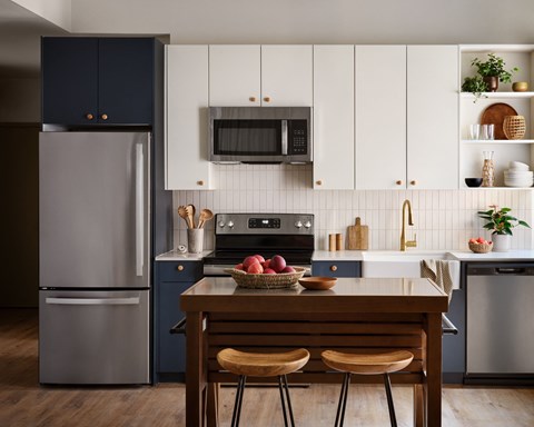 a kitchen with white cabinets and stainless steel appliances and a wooden table