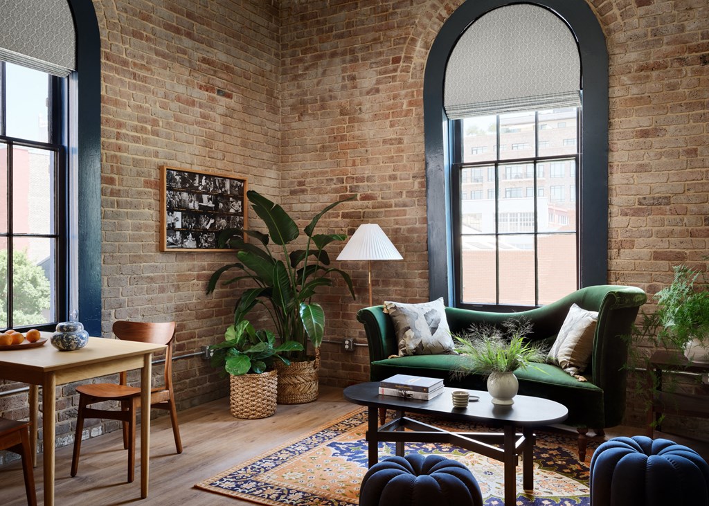 a living room with a brick wall and a green couch