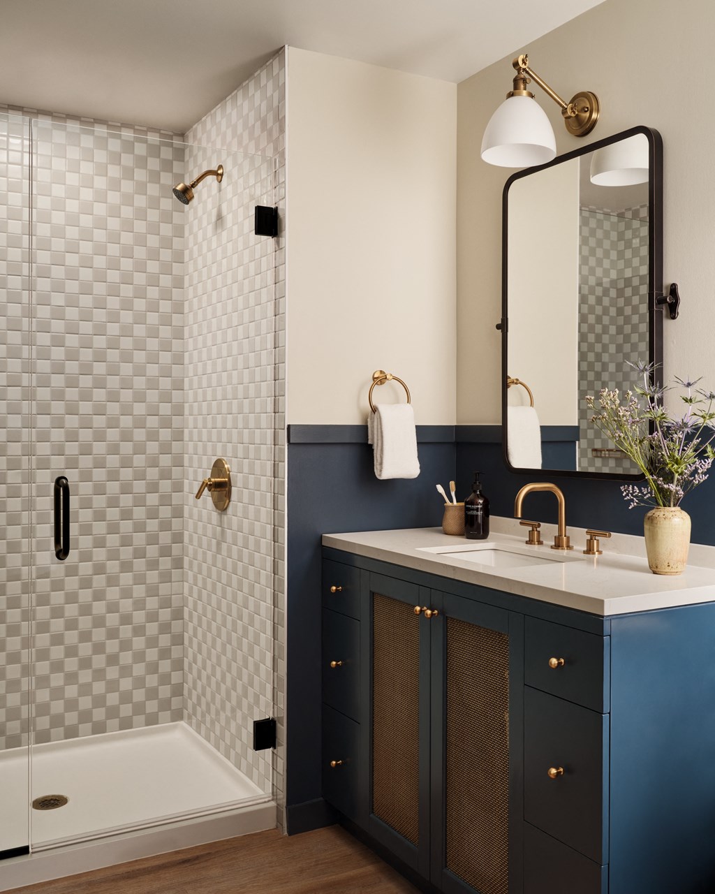 a bathroom with blue cabinets and a shower and a sink and a mirror