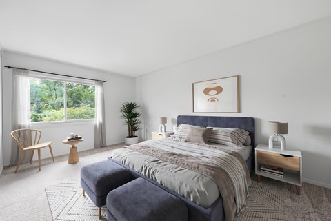 A bedroom with a large bed and a chair by the window.