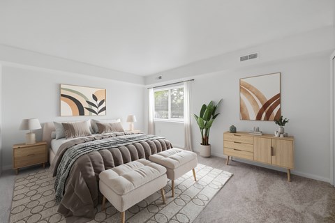 A bedroom with a large bed, a bench, and a painting on the wall.