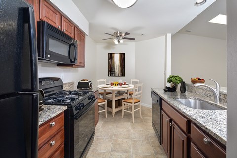 A kitchen with a black refrigerator and a black stove top oven.