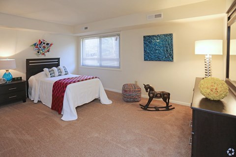 bedroom with a bed, a rocking horse, and a lamp.