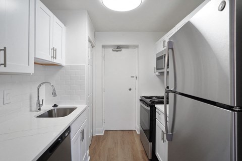 Kitchen with white cabinets, stainless steel appliances, and quarters countertop.