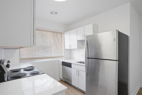 A modern kitchen with a stainless steel refrigerator and white countertops.