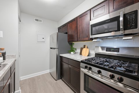 A kitchen with a stove, refrigerator, and microwave.
