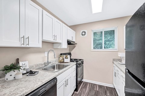 A kitchen with white cabinets and black appliances.