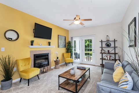 A living room with a yellow chair and a fireplace.