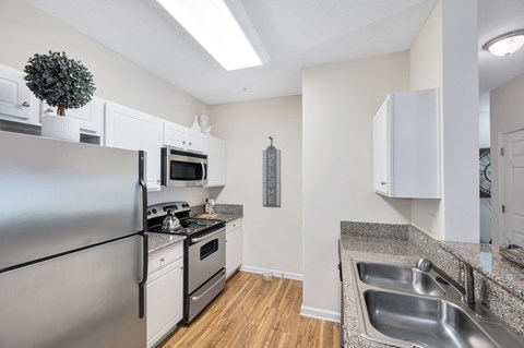 A modern kitchen with a stainless steel refrigerator and a granite countertop.