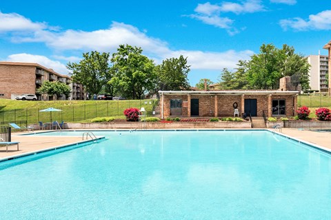 A swimming pool in a sunny day surrounded by buildings and trees.