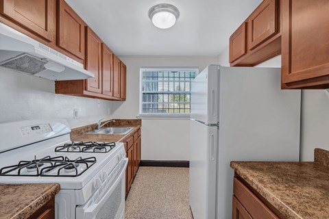 A kitchen with a white stove and a white refrigerator.