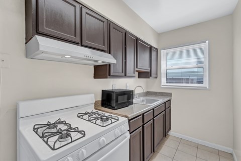 A kitchen with a white stove and brown cabinets.