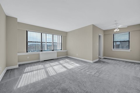A spacious room with a carpeted floor and a window with blinds.