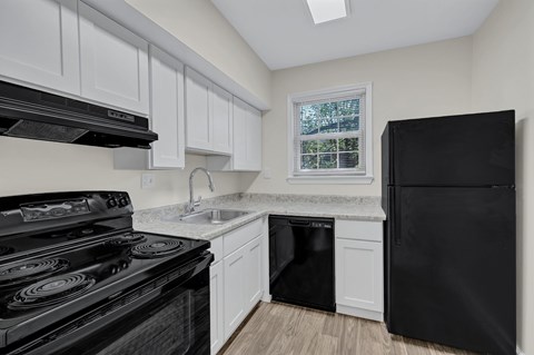 A black stove and oven in a kitchen with white cabinets.