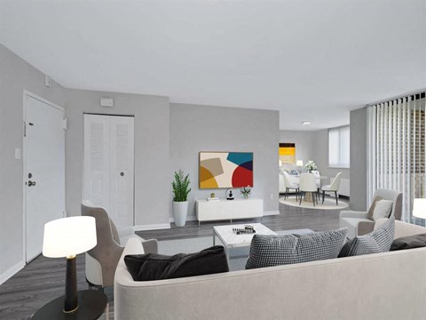 A modern living room with a grey couch, a white chair, and a painting on the wall.