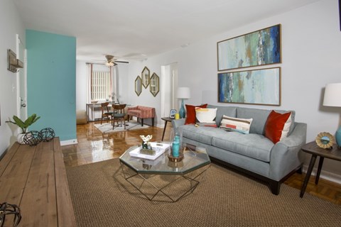 A living room with a grey couch and a glass coffee table.