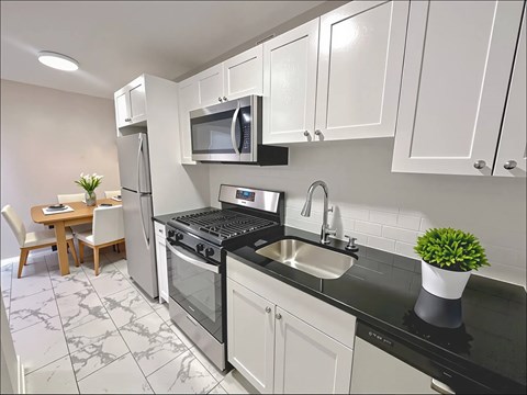 A kitchen with a black counter top and white cabinets.