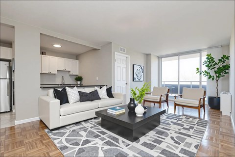 A modern living room with a white sofa, a coffee table, and a large window.