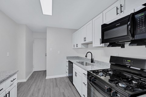 A kitchen with a black stove top oven and a black microwave above the stove.