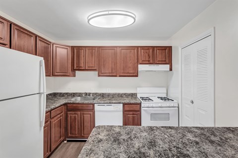 A kitchen with brown cabinets and white appliances.