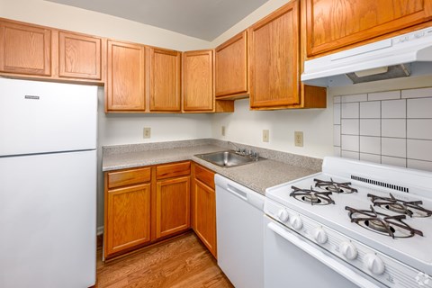 A kitchen with wooden cabinets and a white stove.