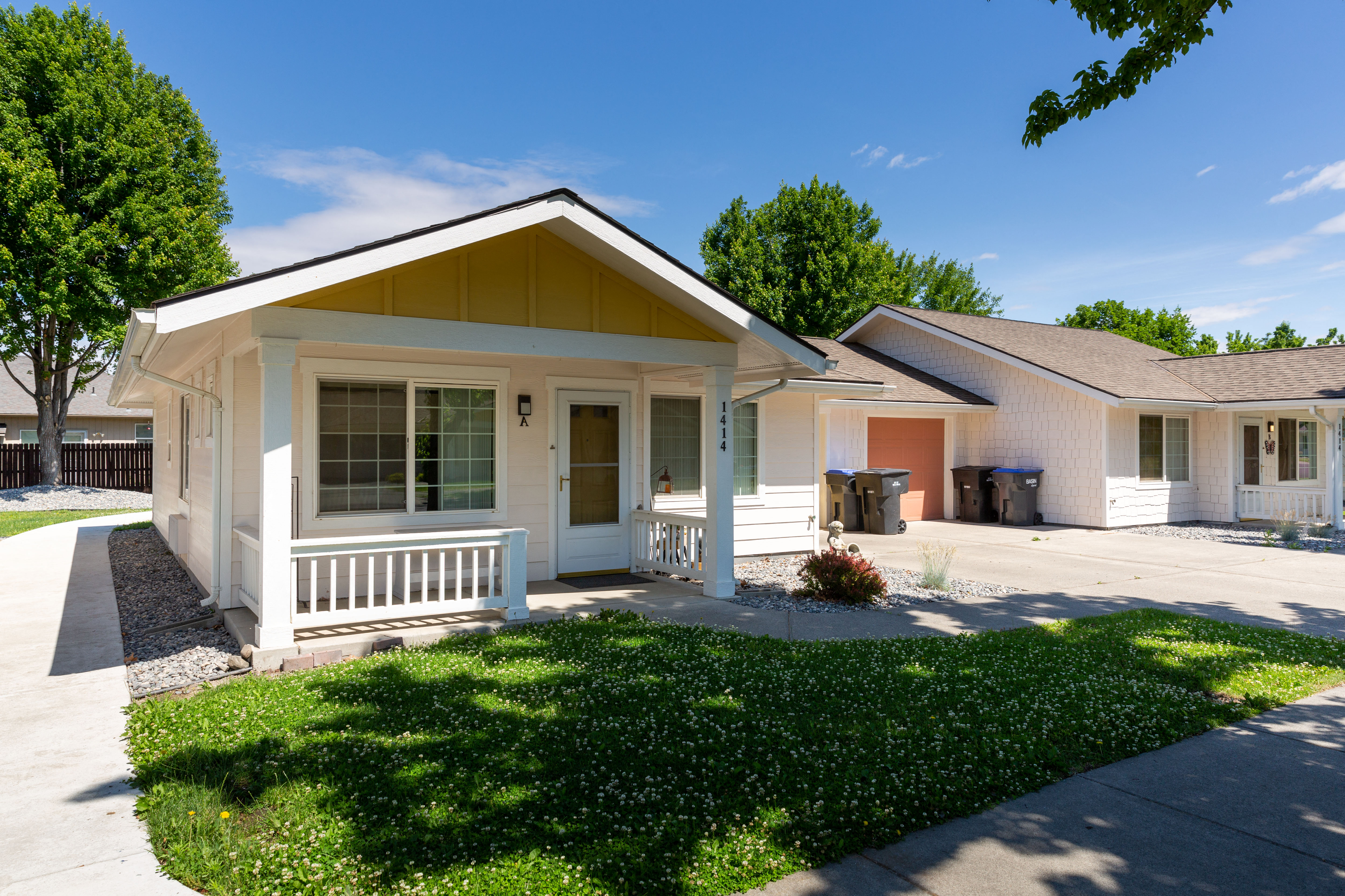 a white bungalow with a porch and a sidewalk in front of a house