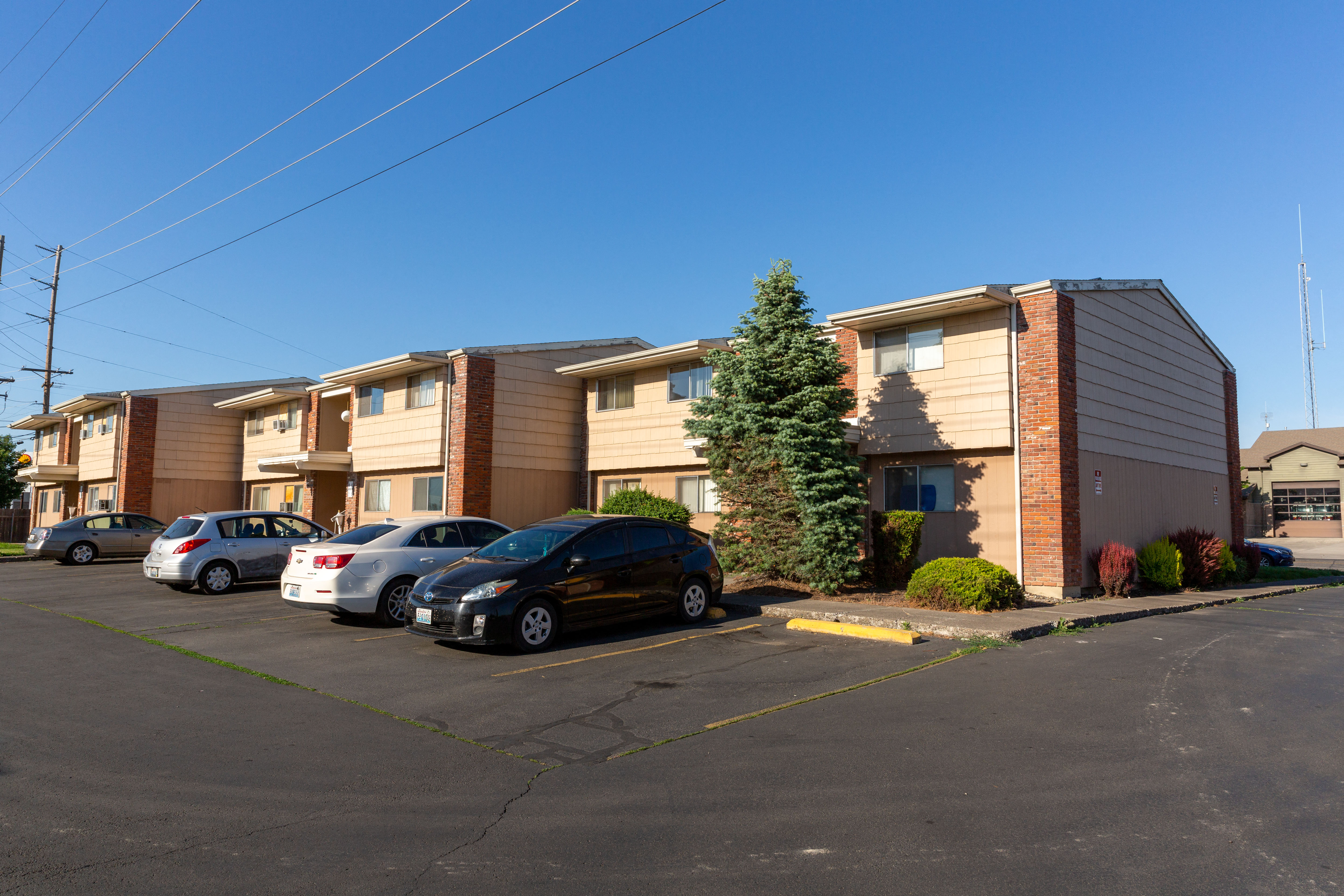 a row of apartment buildings with cars parked in a parking lot