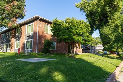 the front of a brick house with a yard and a tree